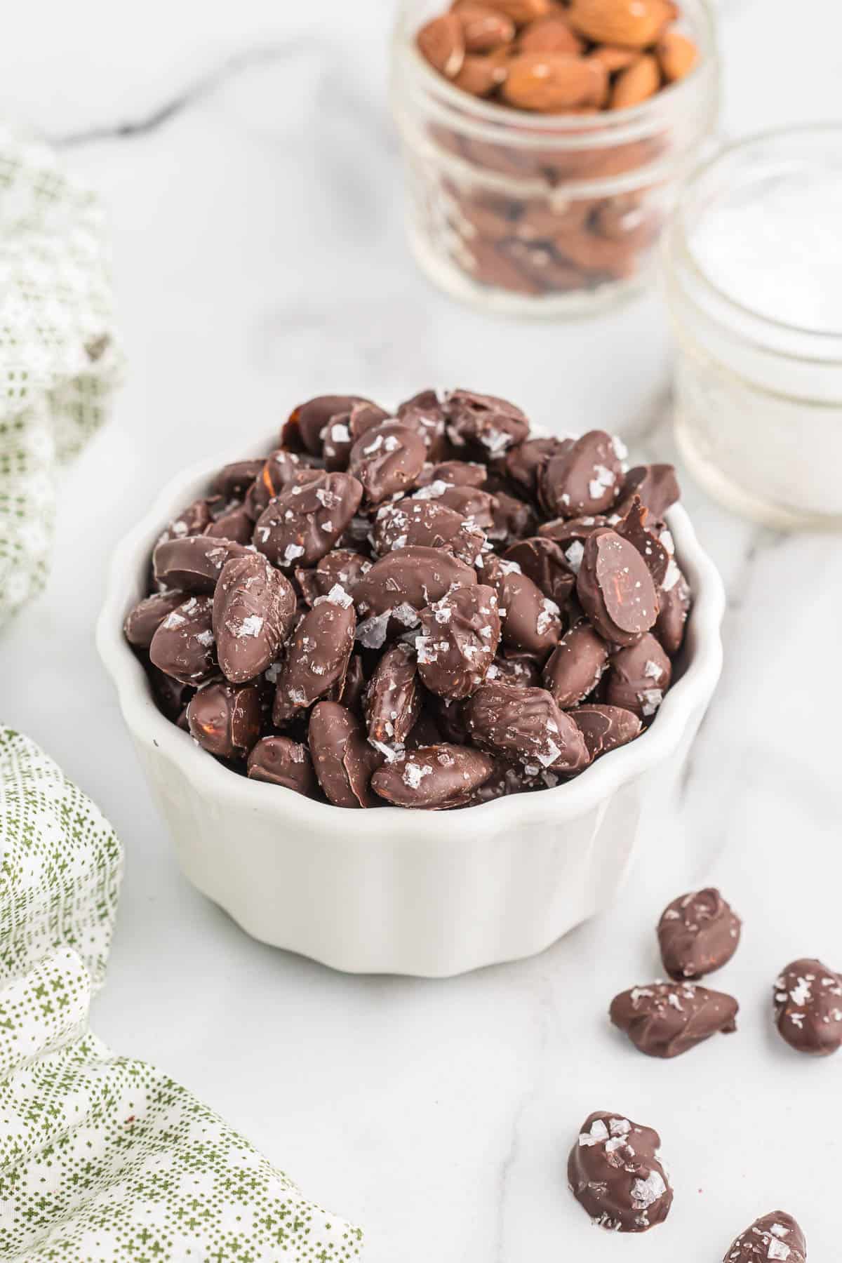 chocolate covered almonds with sea salt in a white bowl