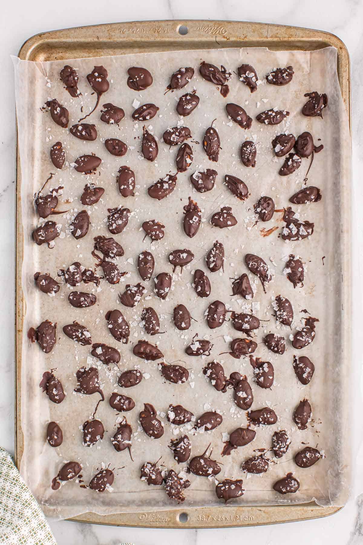 dark chocolate covered almonds on a baking sheet
