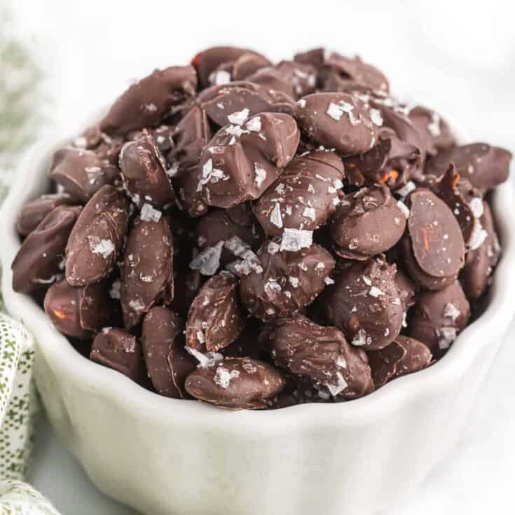 chocolate covered almonds with sea salt in a white bowl