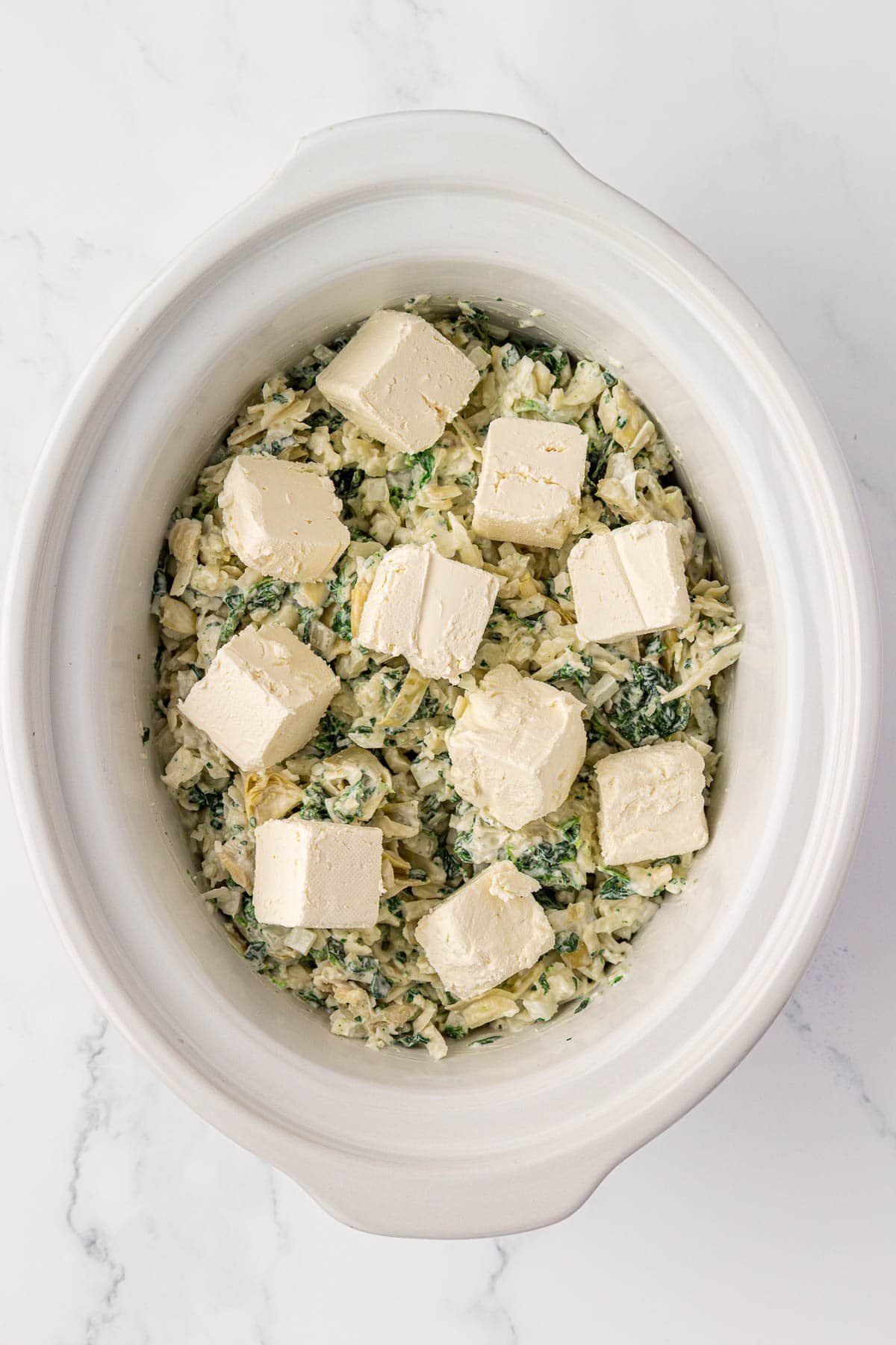 cream cheese chunks on top of the spinach artichoke dip mixture