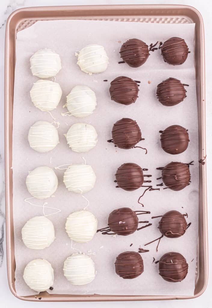 white and dark chocolate oreo truffles on a lined baking sheet