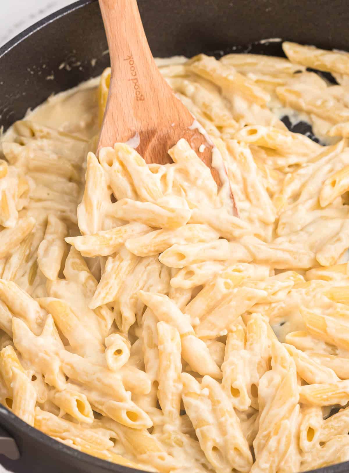 creamy penne pasta on a wooden spoon