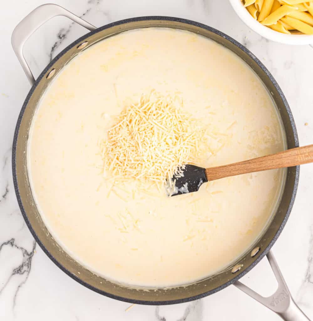 adding parmesan cheese to the cream sauce