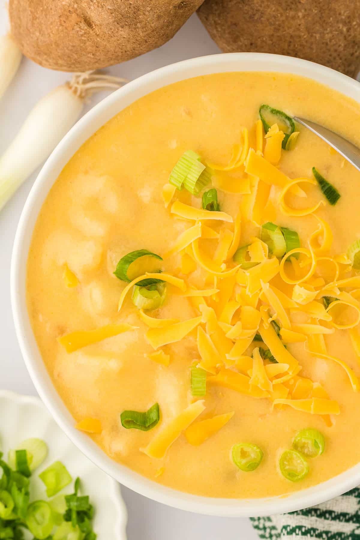 potato soup in a bowl topped with green onions and cheddar cheese