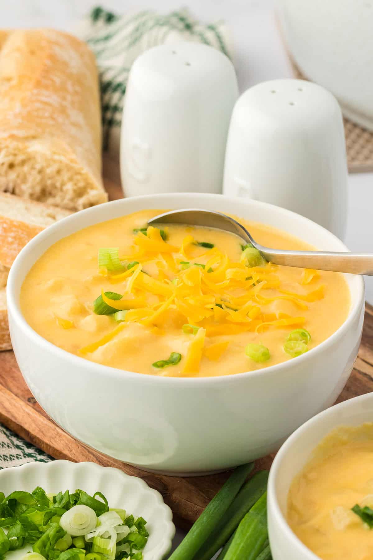 potato soup in a bowl topped with green onions and cheddar cheese
