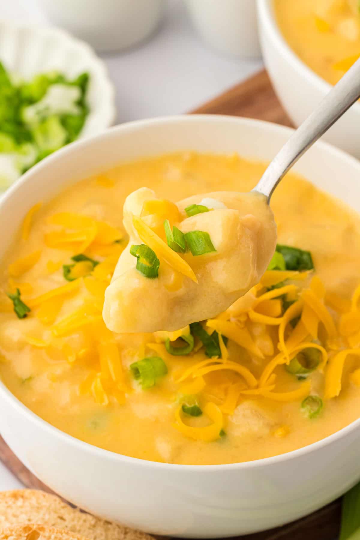 potato soup in a bowl topped with green onions and cheddar cheese