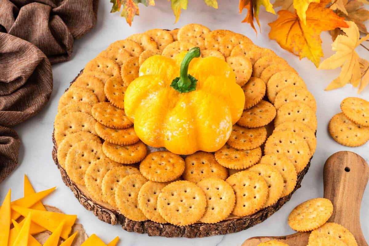 pumpkin shaped cheese ball on a platter with crackers