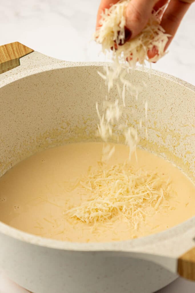 adding parmesan cheese to the sauce