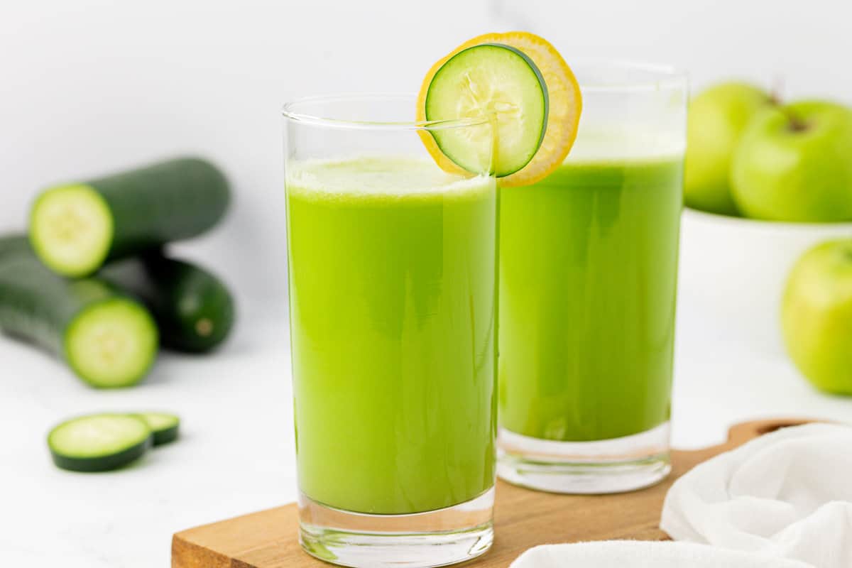 juice in a glass with a cucumber and lemon slice on the rim