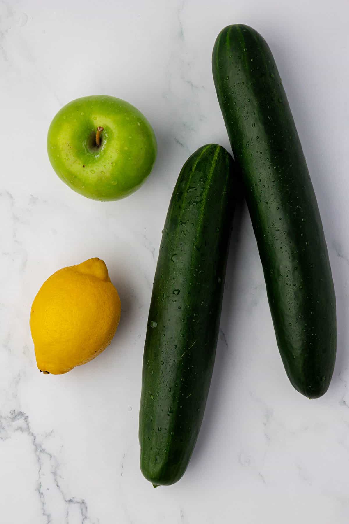 two cucumbers, a lemon, and a green apple