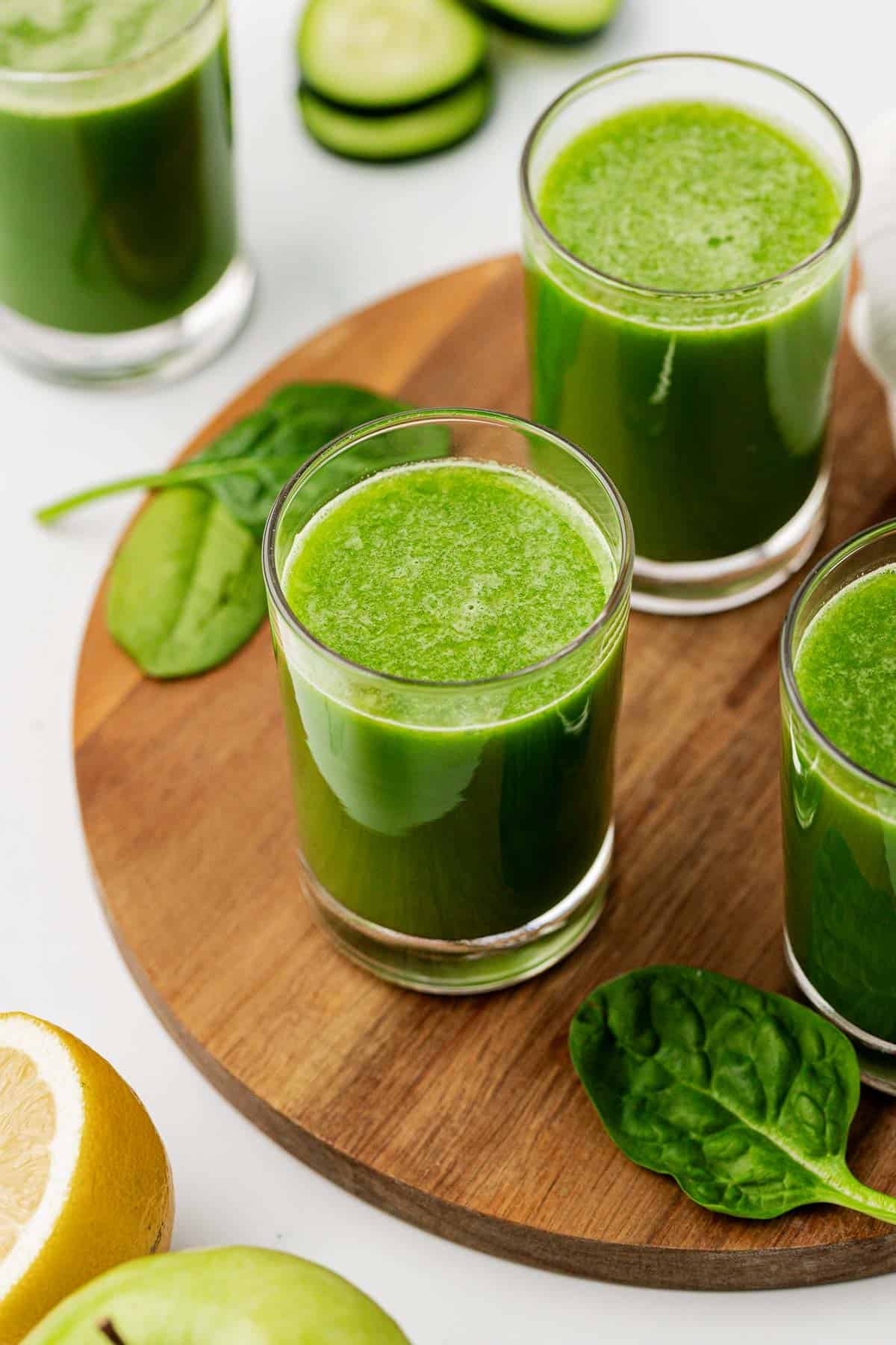spinach juice in a glass on a wooden cutting board