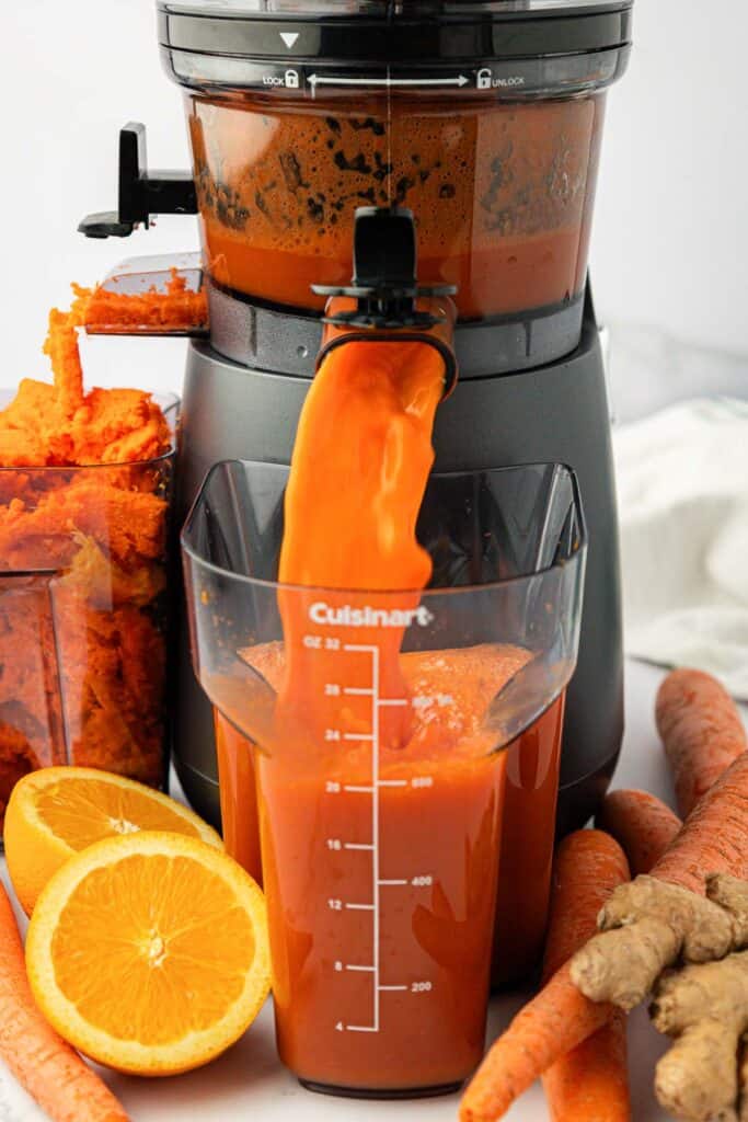 carrot juice pouring out of a juicer