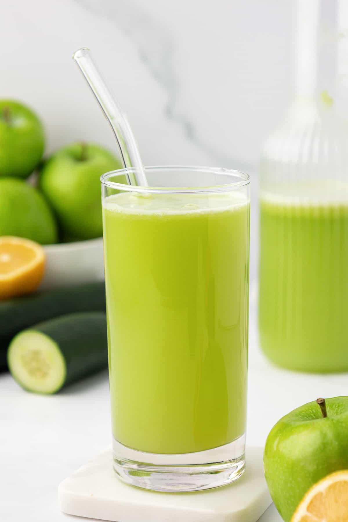 green apple juice in a tall glass with a straw