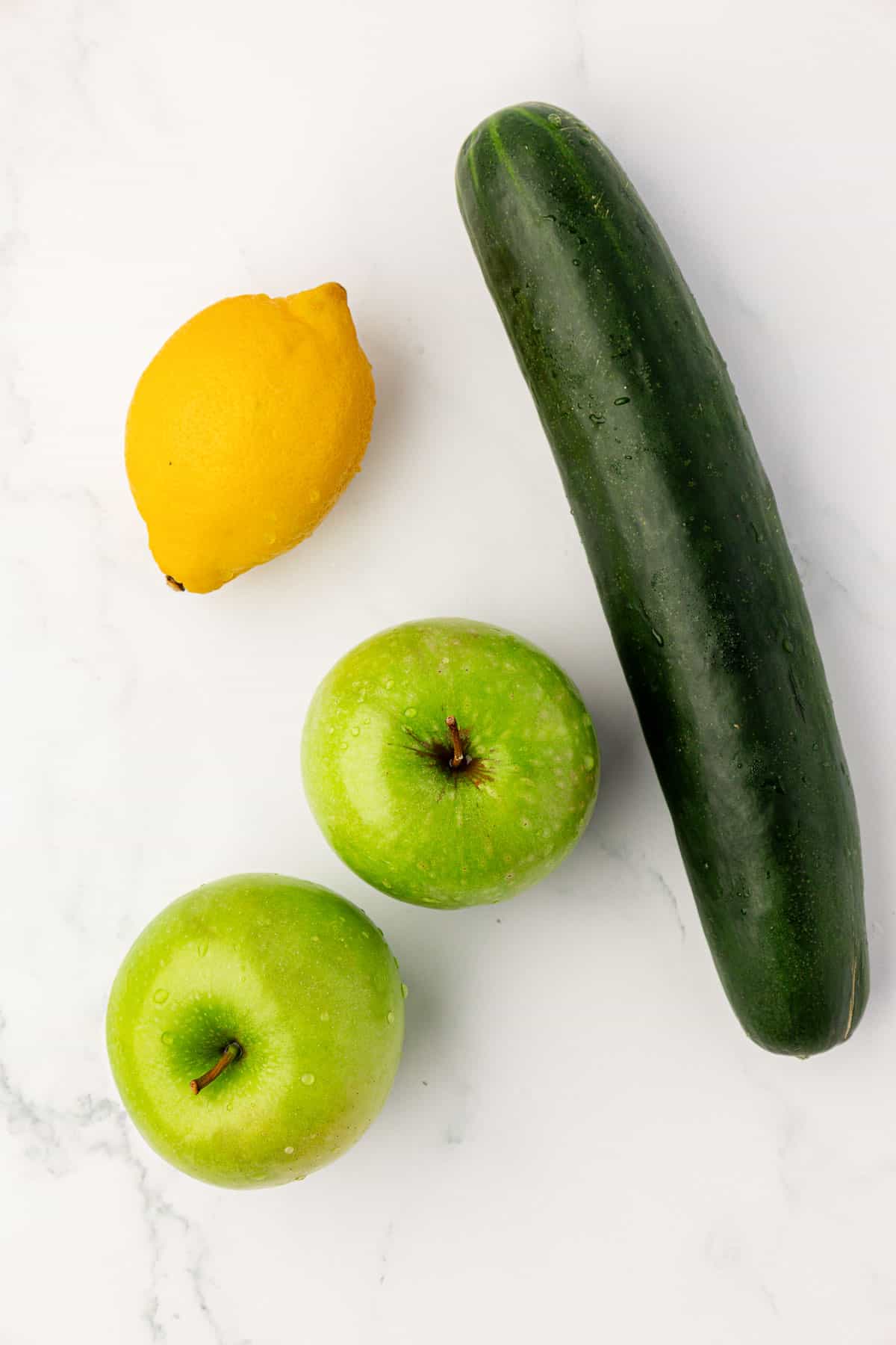a lemon, two green apples, and a cucumber