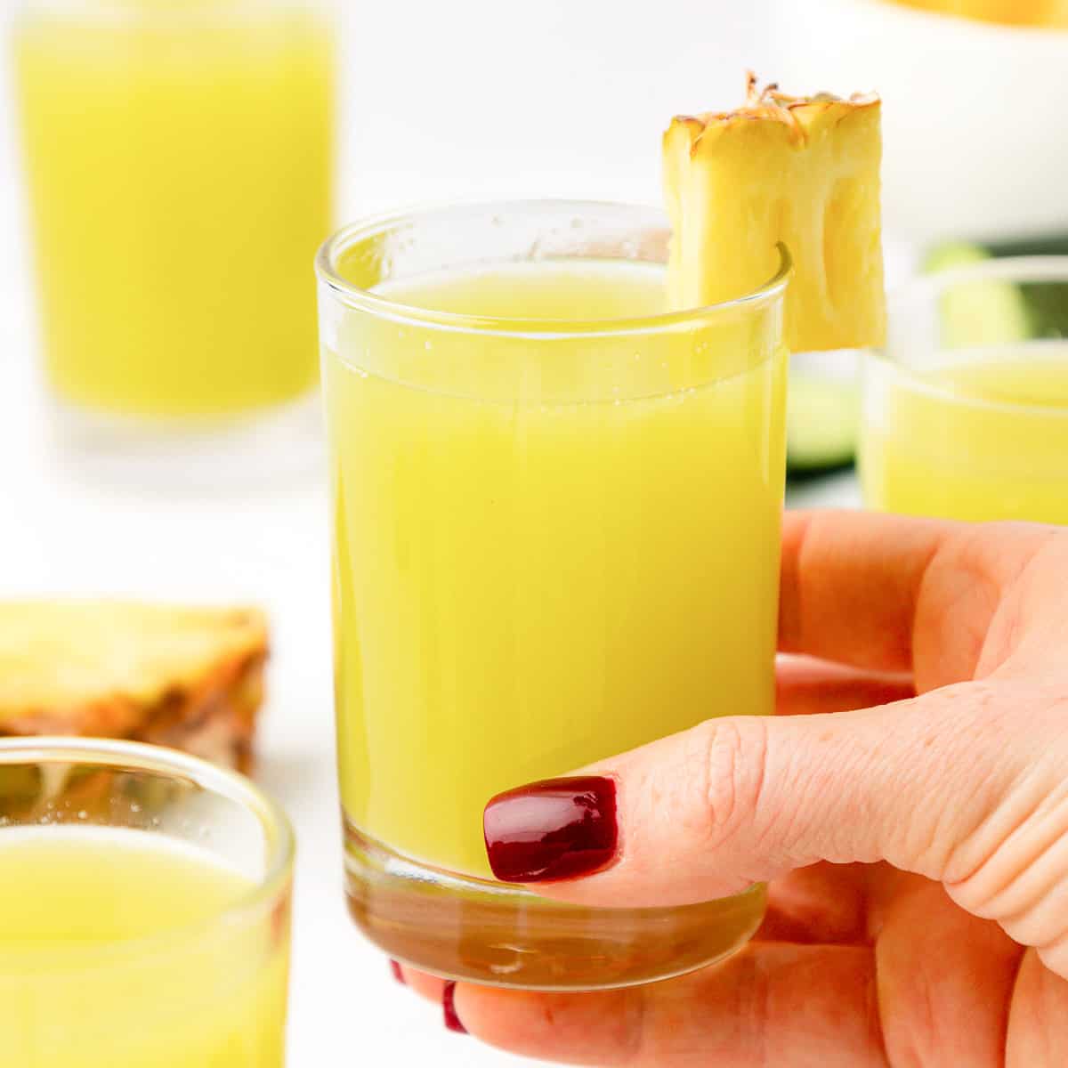 hand holding a glass of pineapple cucumber juice