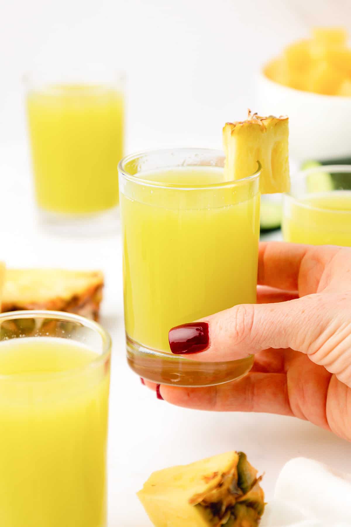 hand holding a glass of pineapple cucumber juice