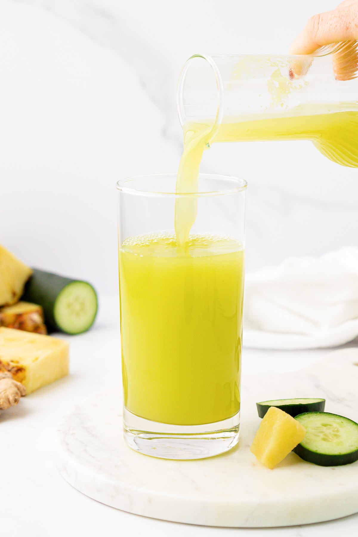 pouring pineapple cucumber juice into a glass