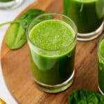 spinach juice in a glass on a wooden cutting board