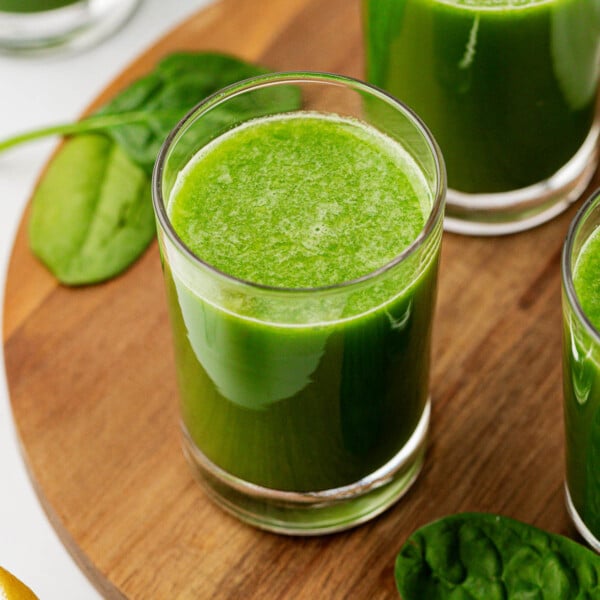 spinach juice in a glass on a wooden cutting board