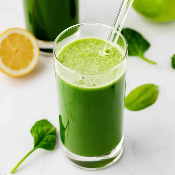 spinach juice in a glass with a straw
