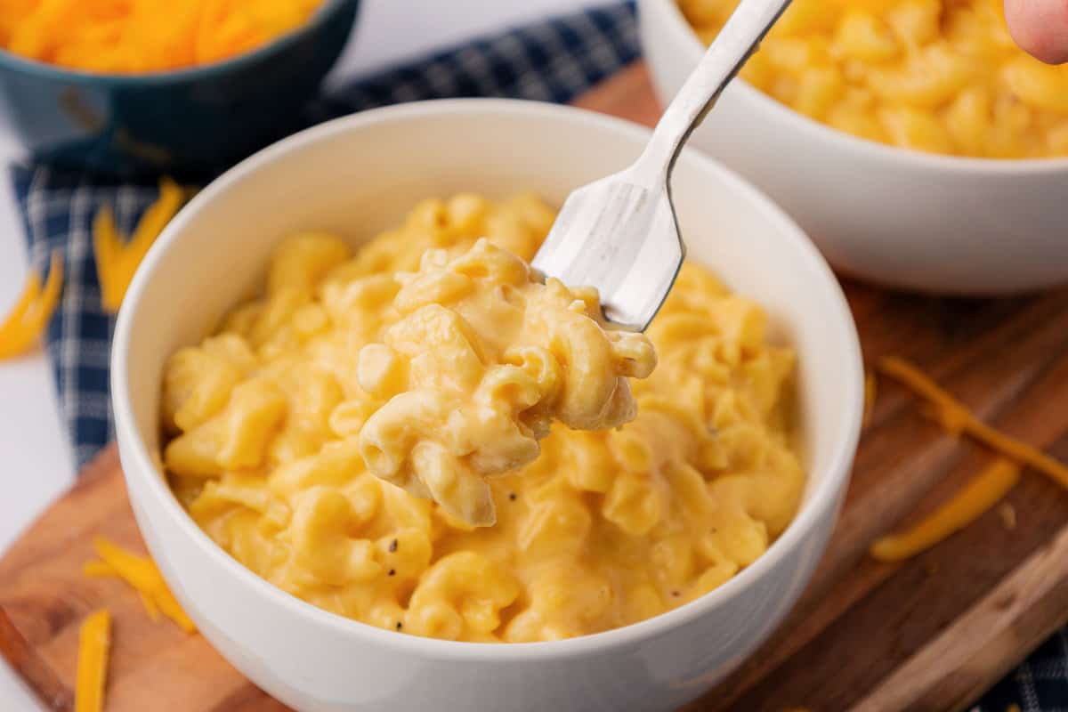 a fork taking a bite of mac and cheese from a bowl