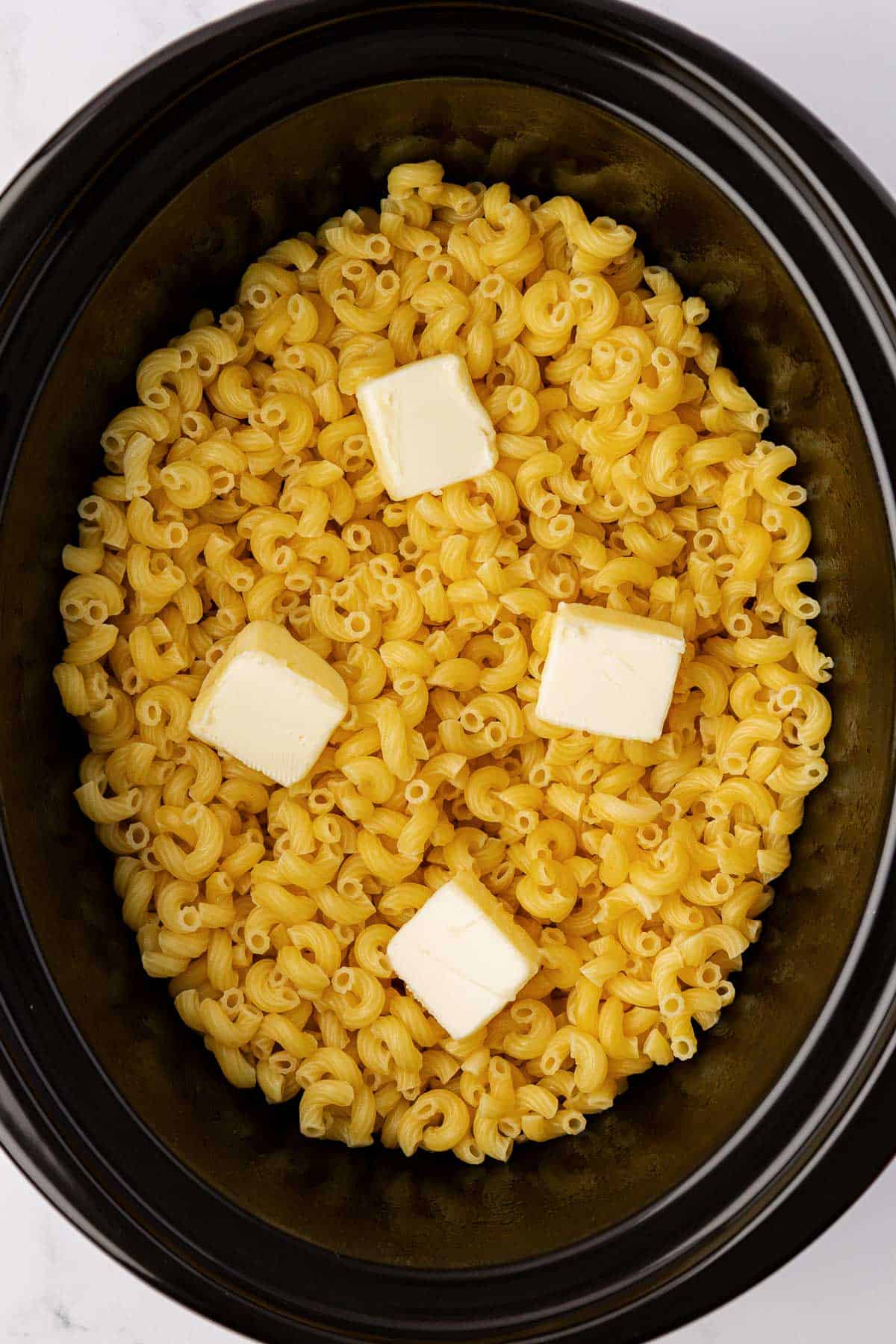 butter on macaroni noodles in a crock pot
