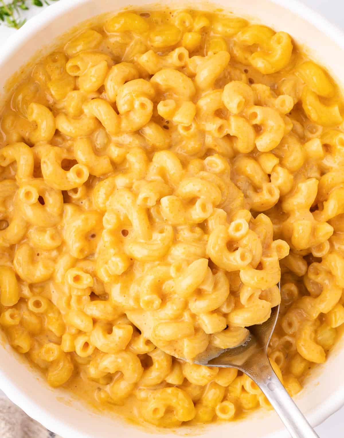 butternut squash mac and cheese in a bowl with a serving spoon