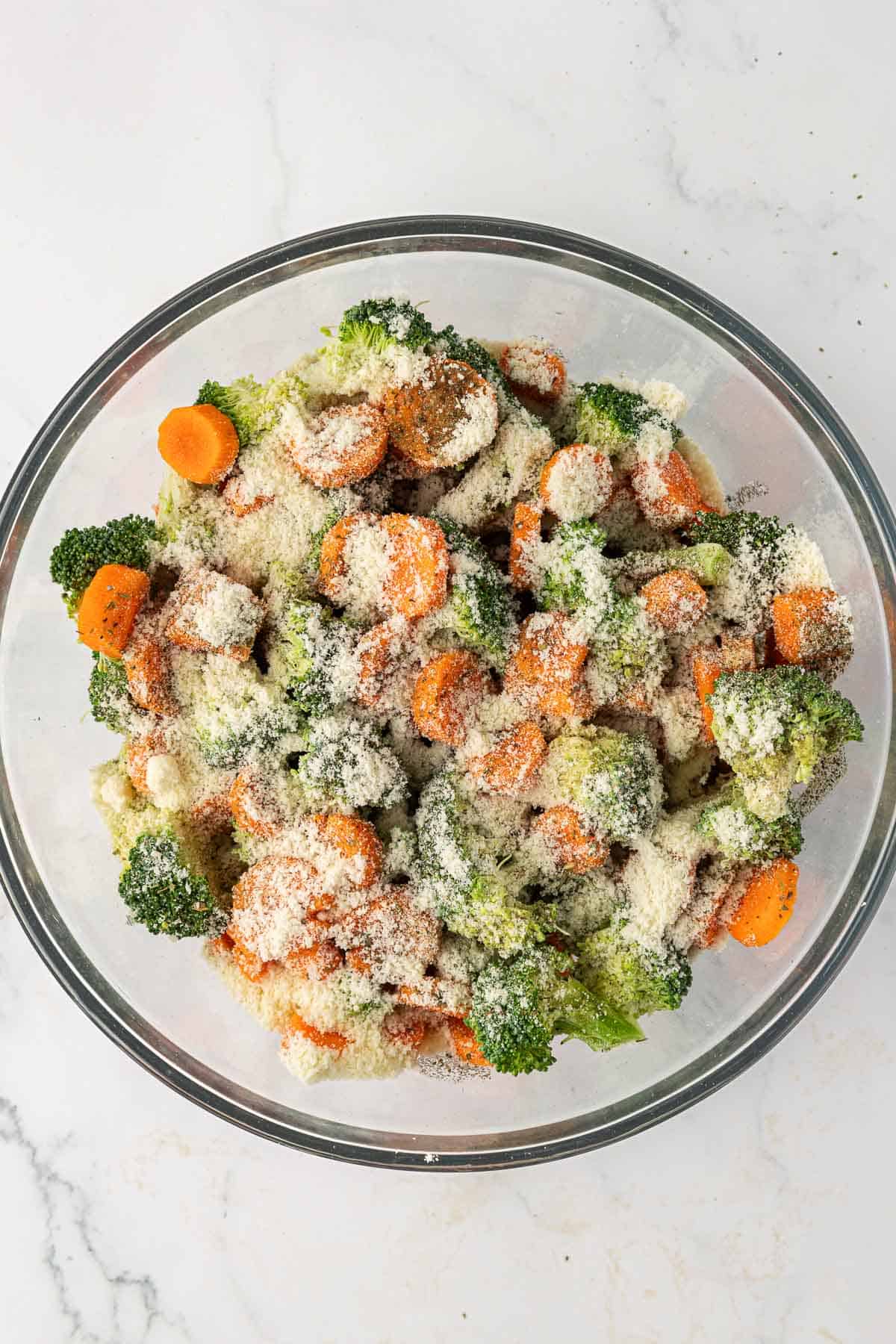 broccoli, carrots, parmesan, oil, and spices in a mixing bowl