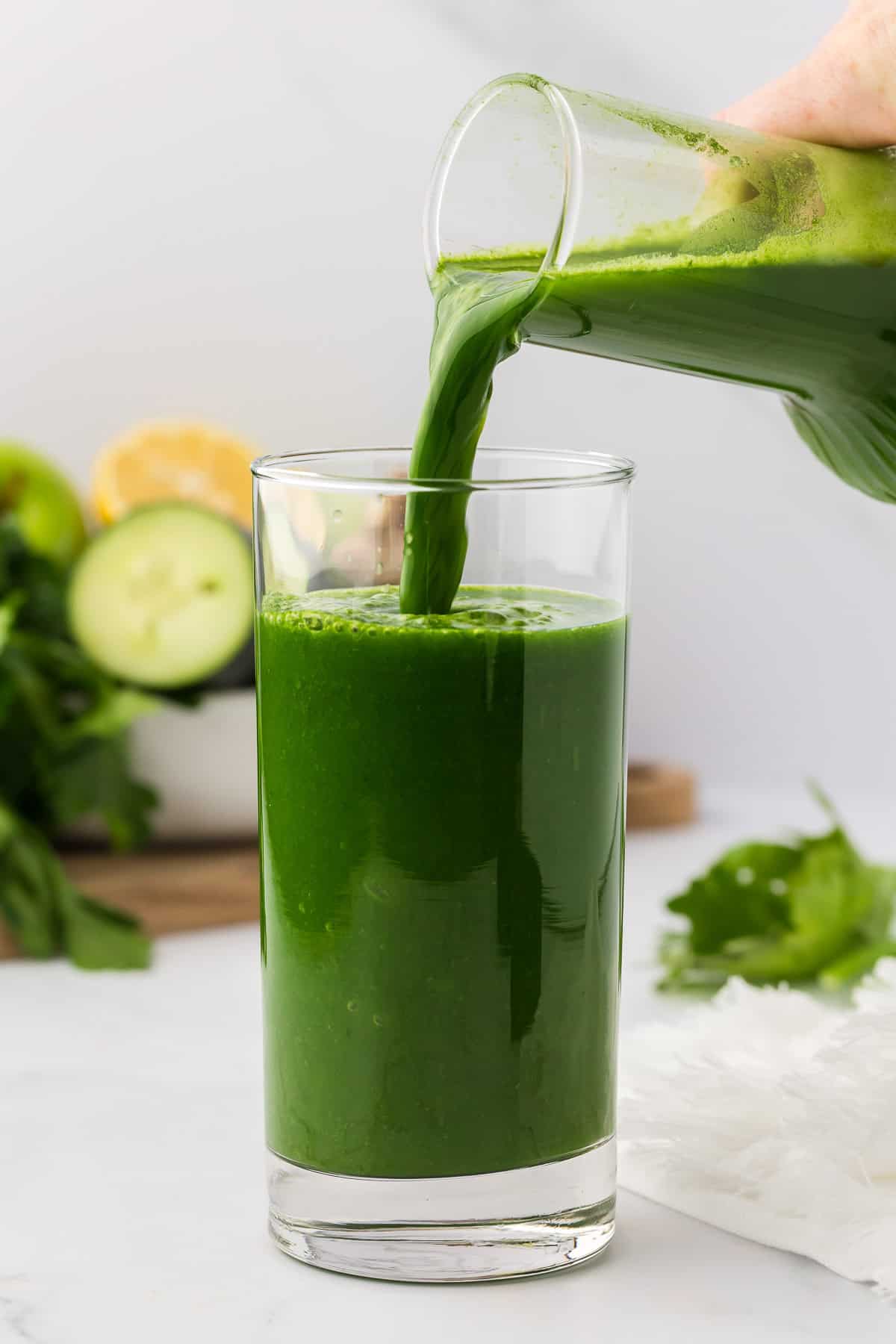 pouring green juice into a glass