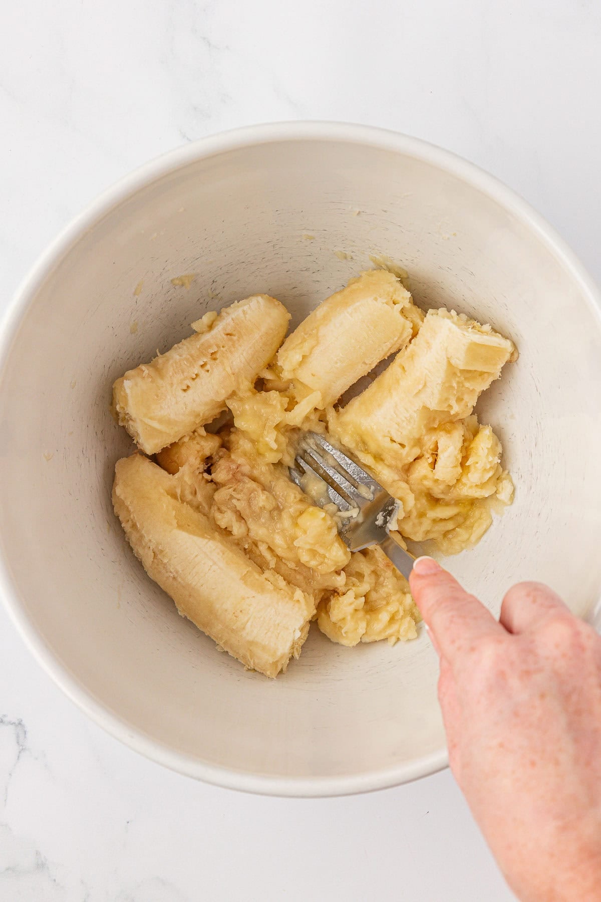 mashing bananas in a mixing bowl