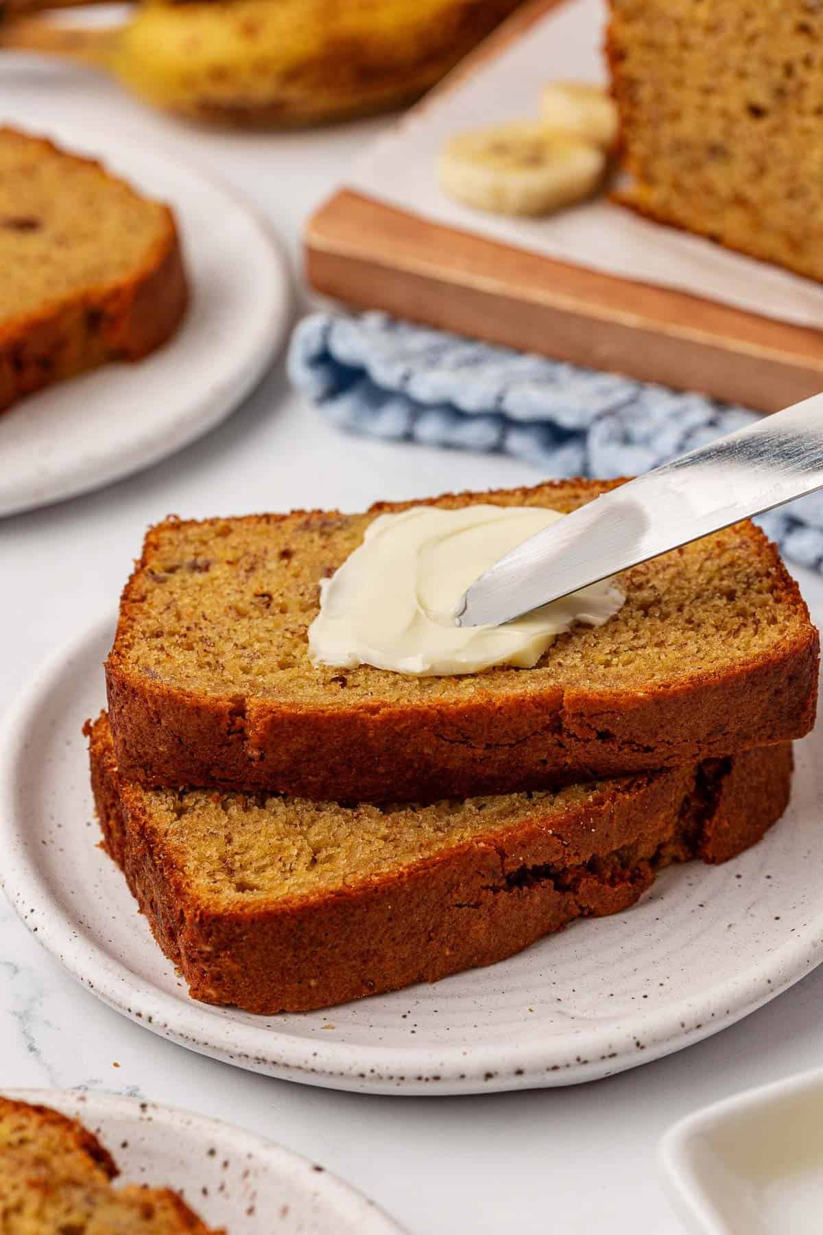 spreading butter onto a slice of banana bread