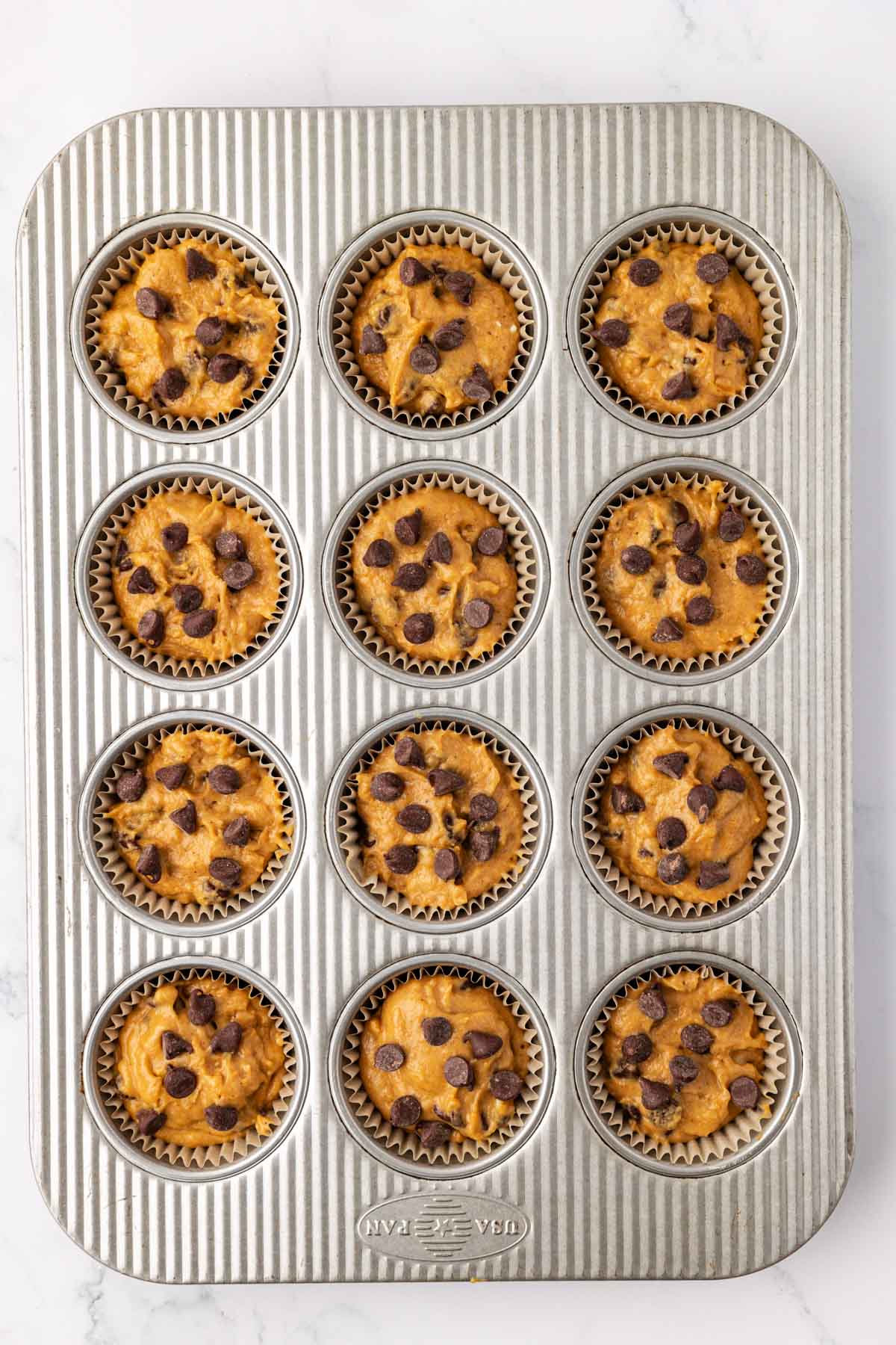 pumpkin chocolate chip muffin batter in the muffin tin