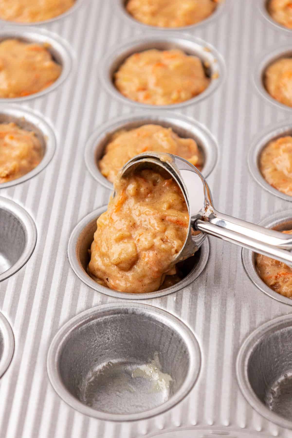 mini cookie scoop scooping batter into a mini muffin tin