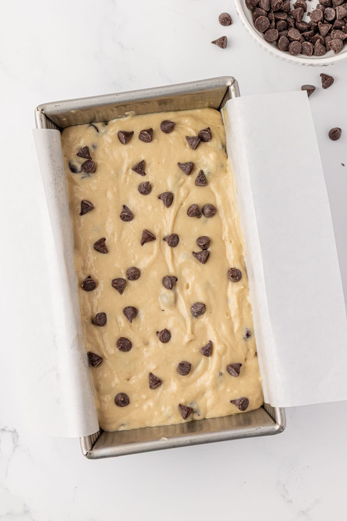 loaf pan with batter and chocolate chips sprinkled on top