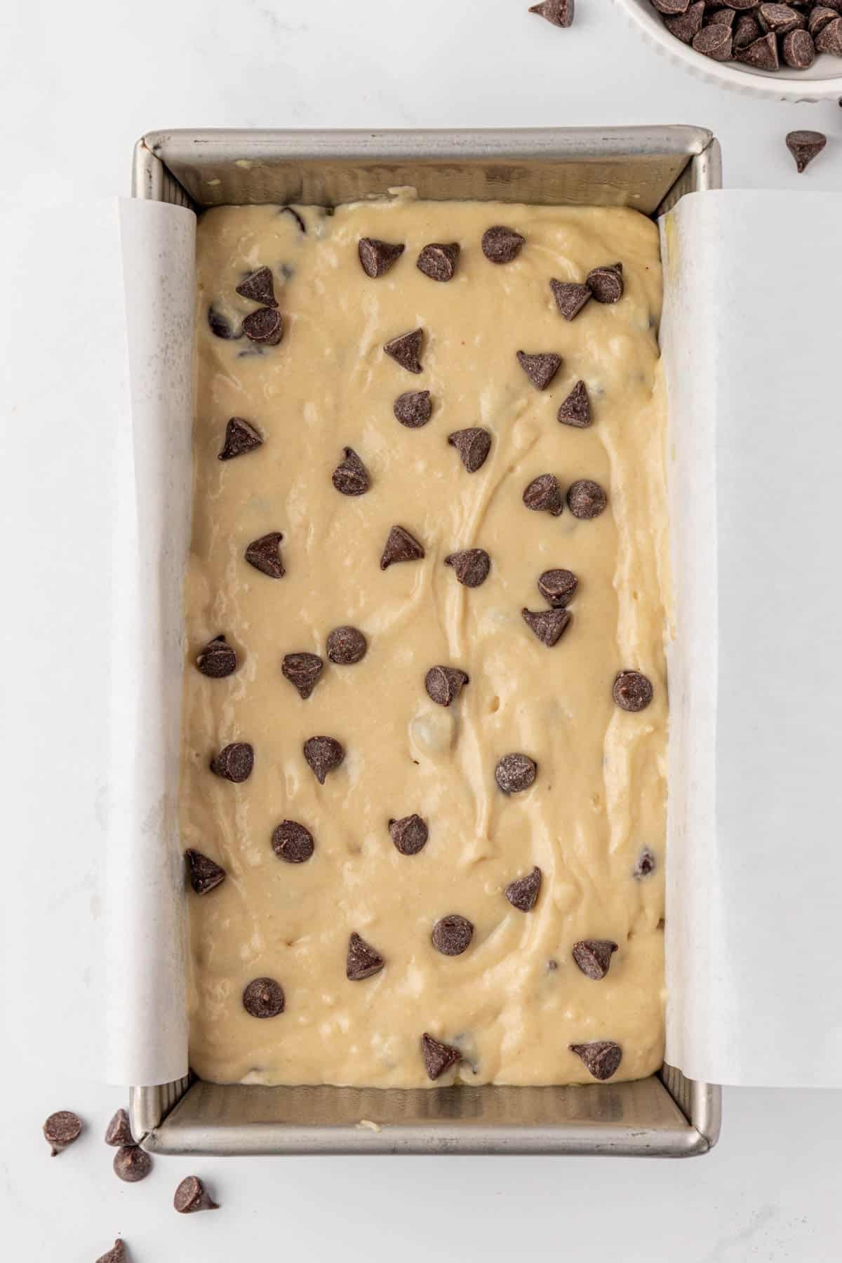 loaf pan with batter and chocolate chips sprinkled on top