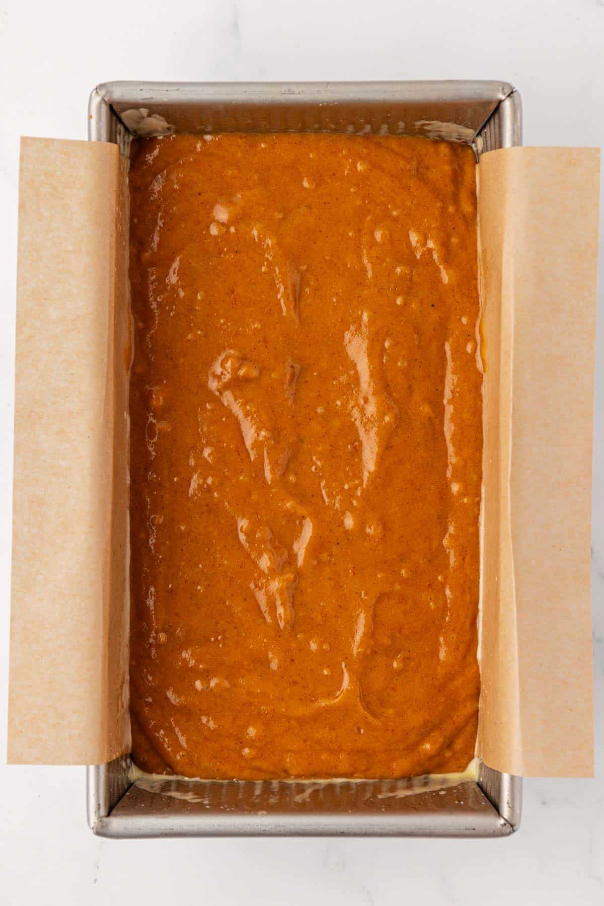 pumpkin bread batter spread in a loaf pan