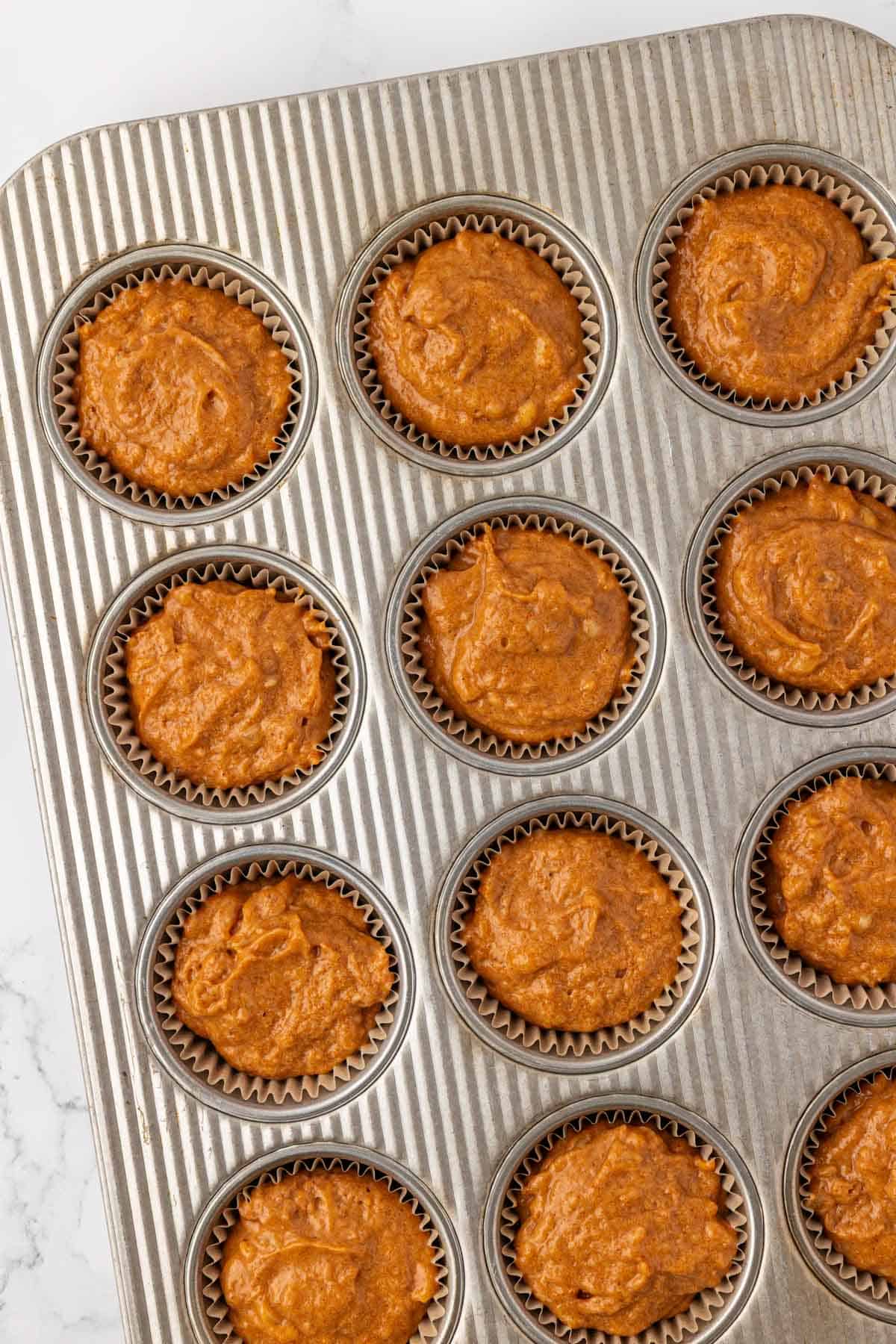 muffin tin filled with pumpkin banana muffin batter