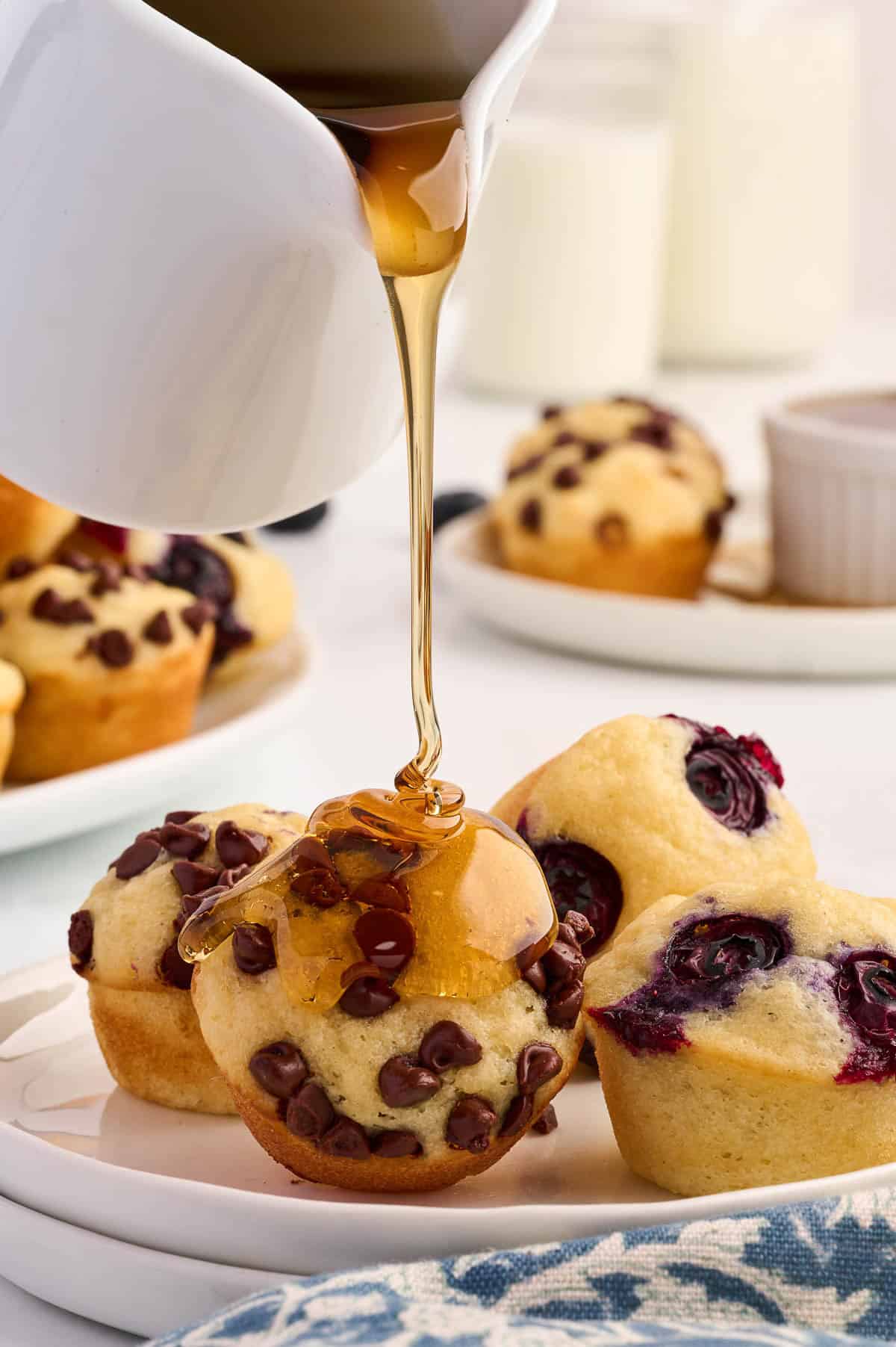 drizzling maple syrup over a pancake muffin