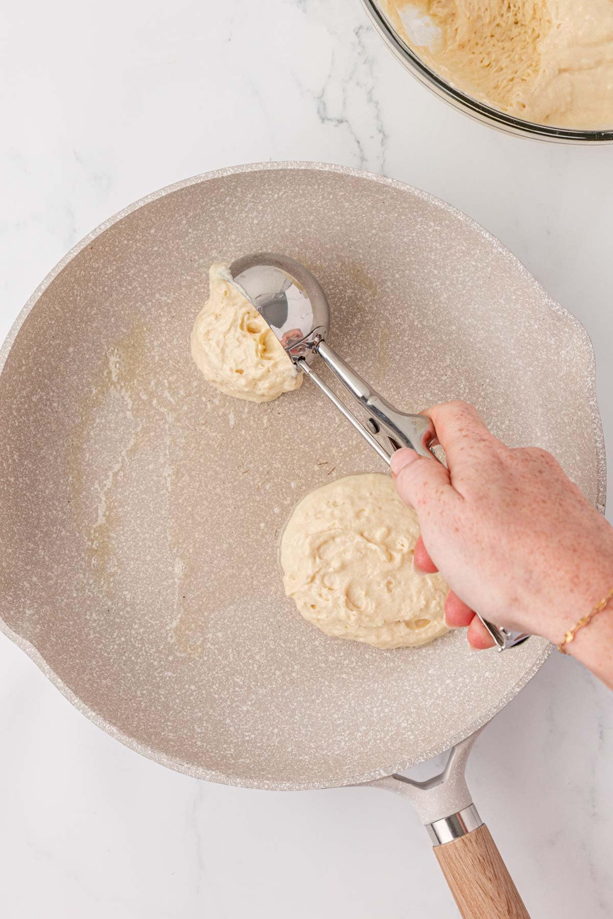 scooping pancake batter into a skillet