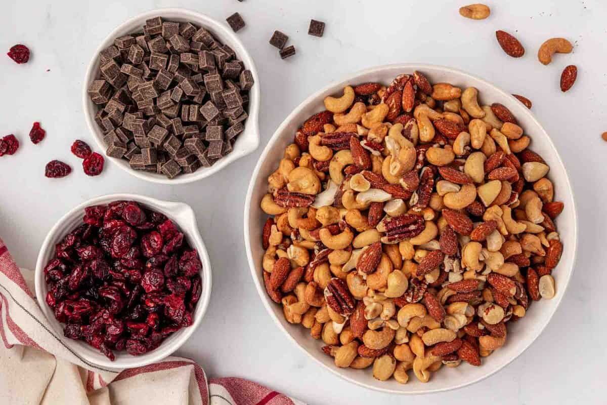 three bowls with roasted nuts, cranberries, and chocolate chunks