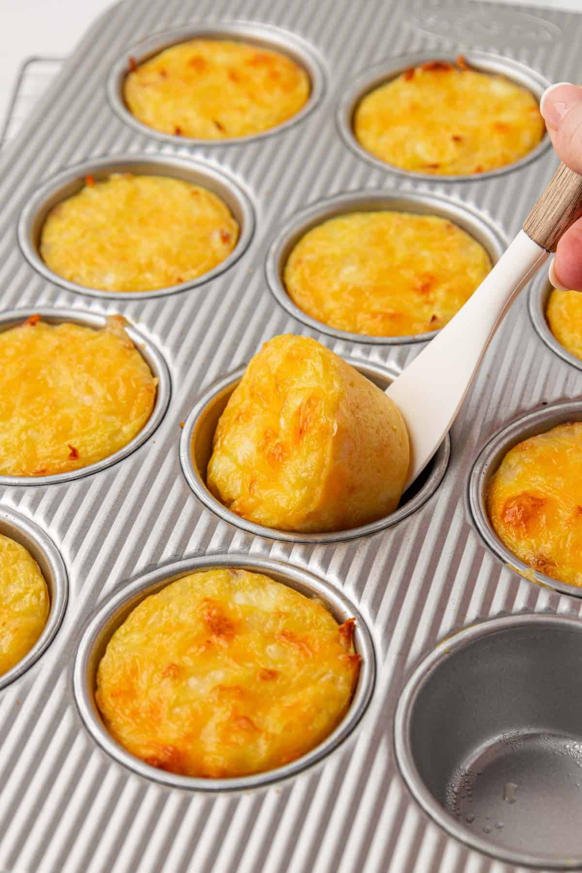 using a mini spatula to remove hash brown egg cups from the pan