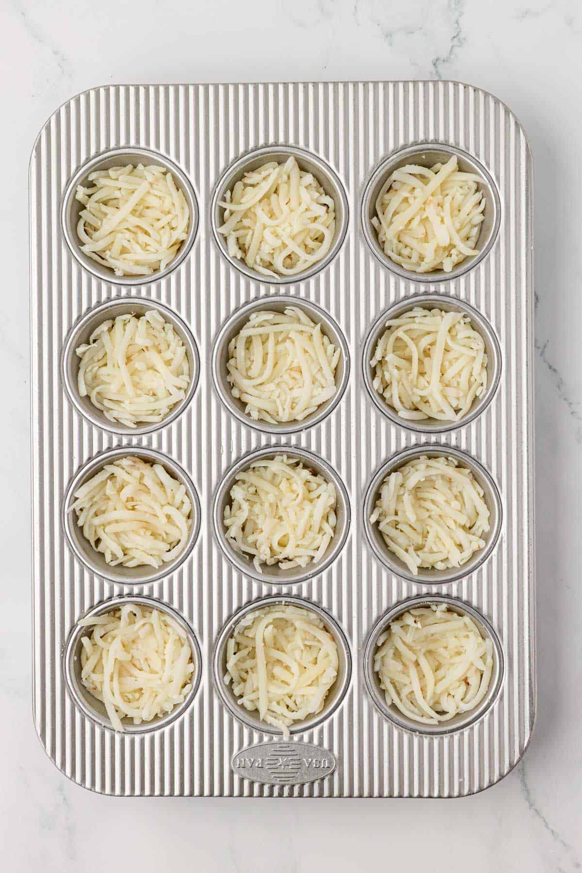 hash browns pressed down in a muffin tin