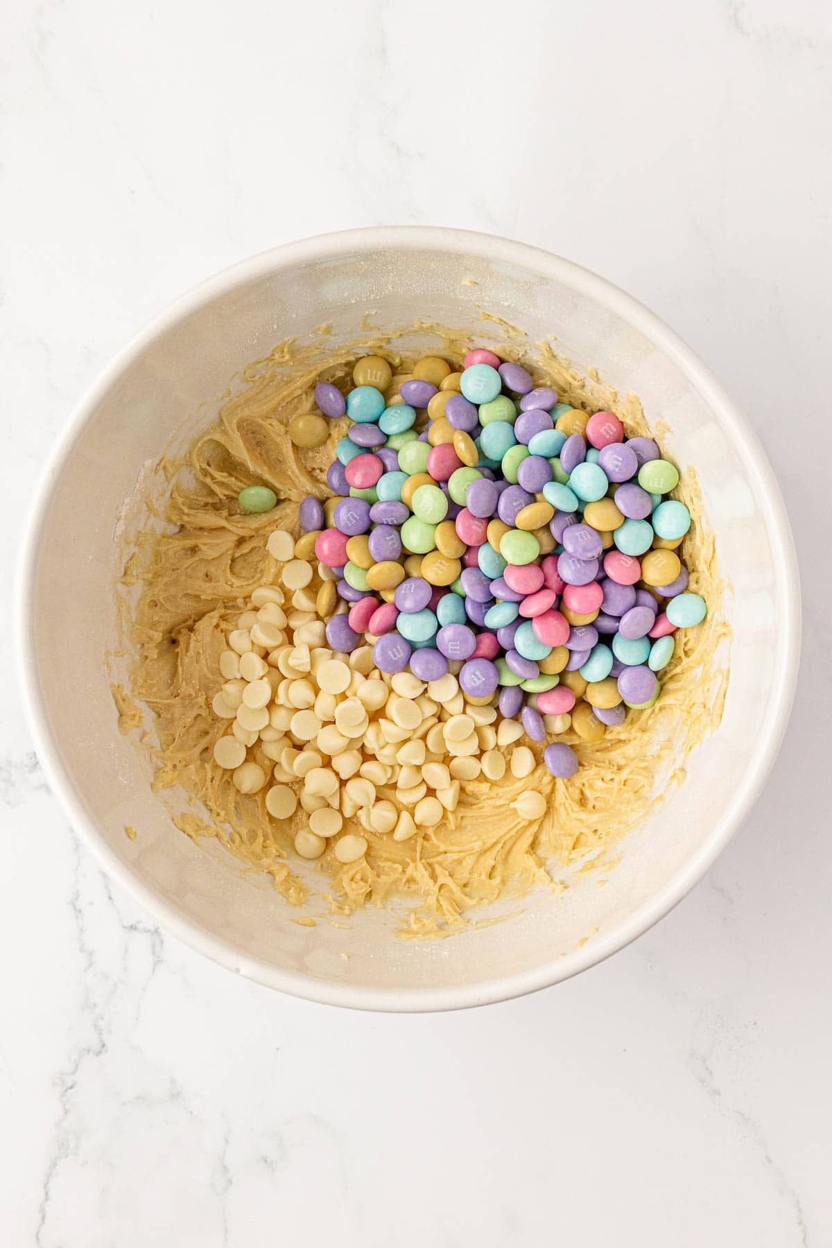 adding the white chocolate chips and m&m's to the cake mix batter