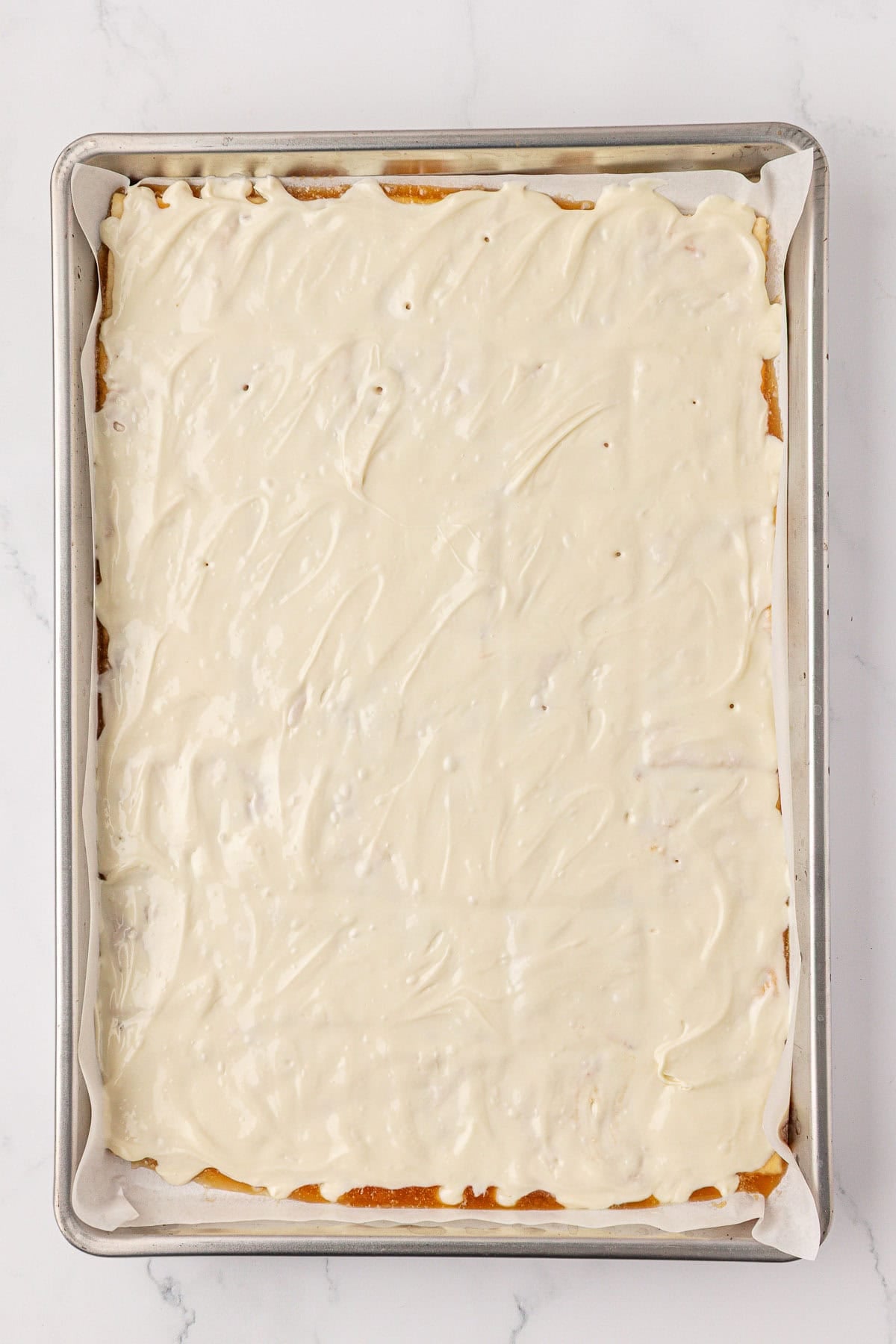 melted white chocolate spread over the saltine crackers