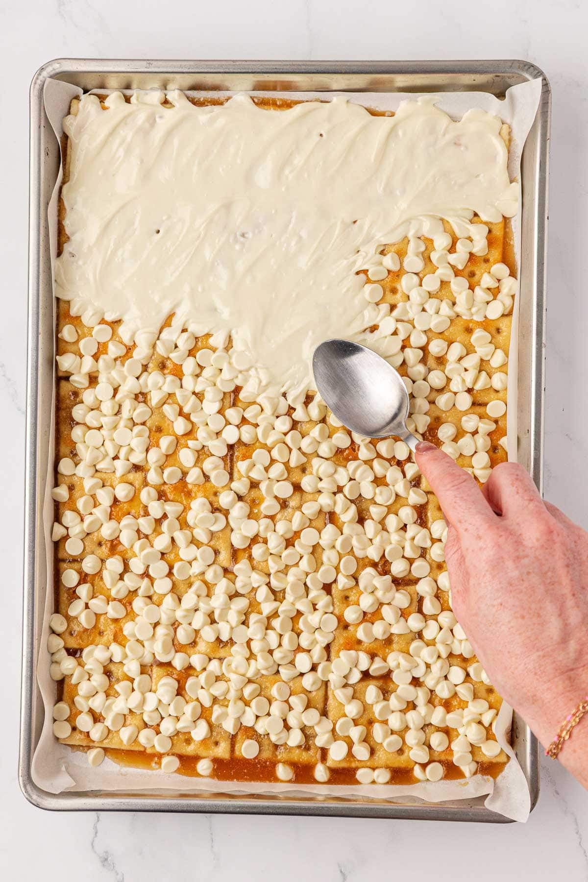 using a spoon to spread the melted white chocolate chips
