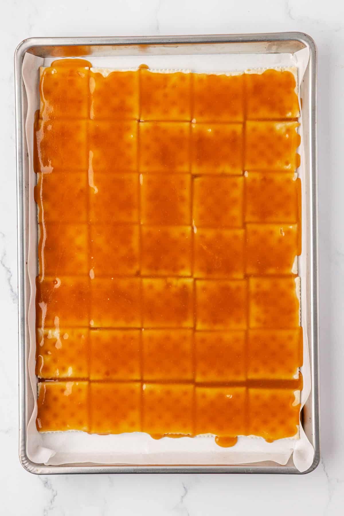 toffee spread over saltines on a baking sheet