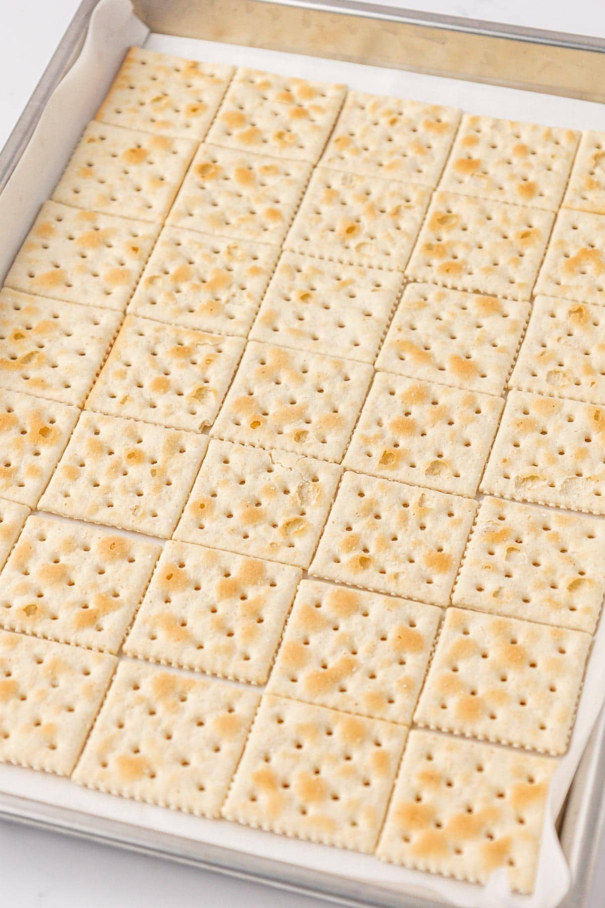 saltine crackers lined on a baking sheet