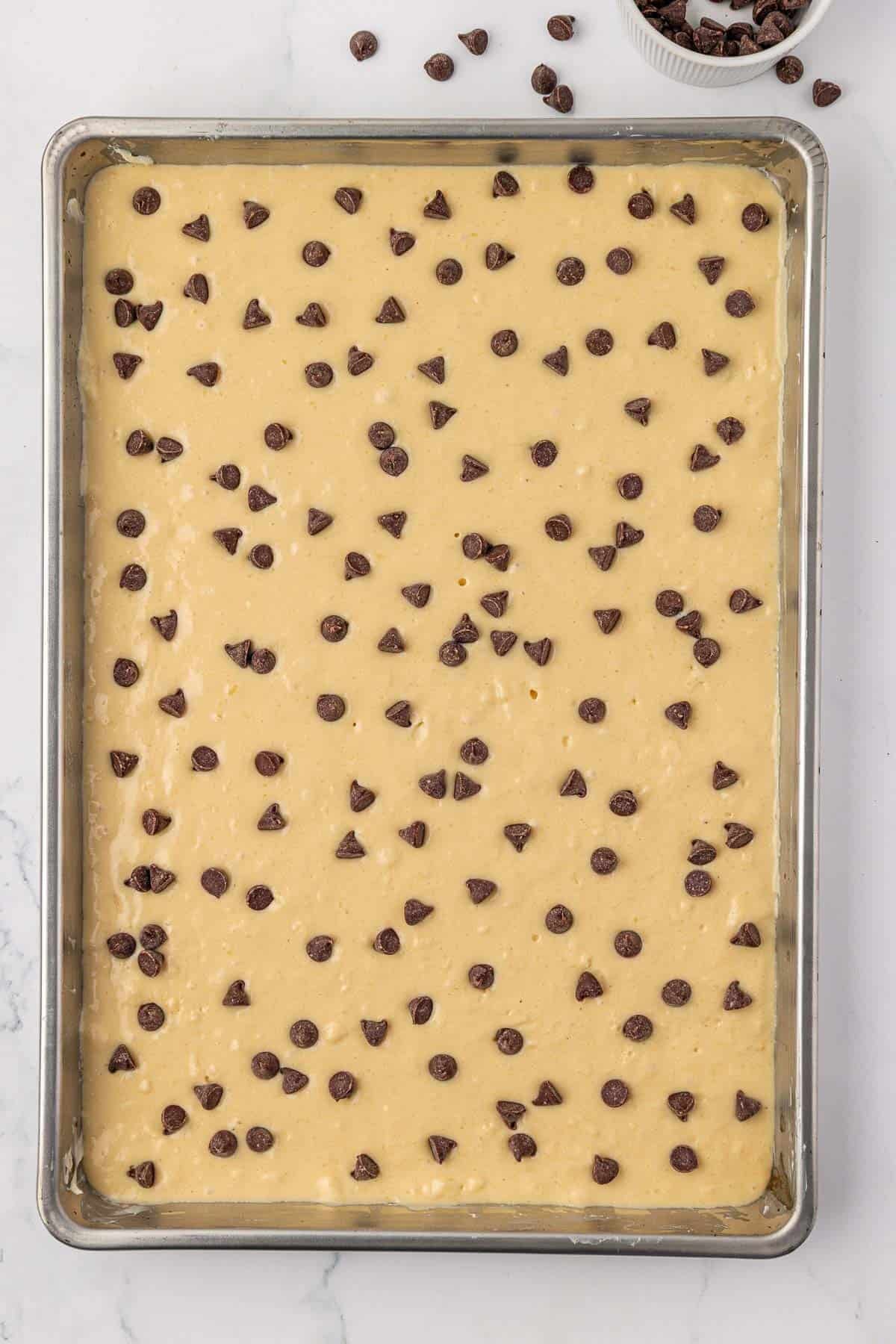 batter spread out on a sheet pan and topped with chocolate chips