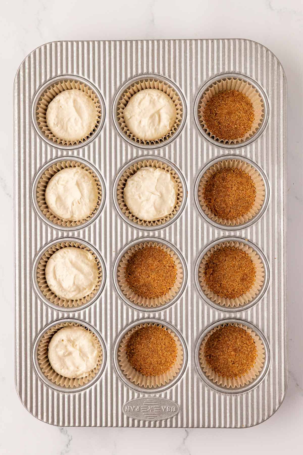 adding the cheesecake filling over the top of the graham cracker crusts