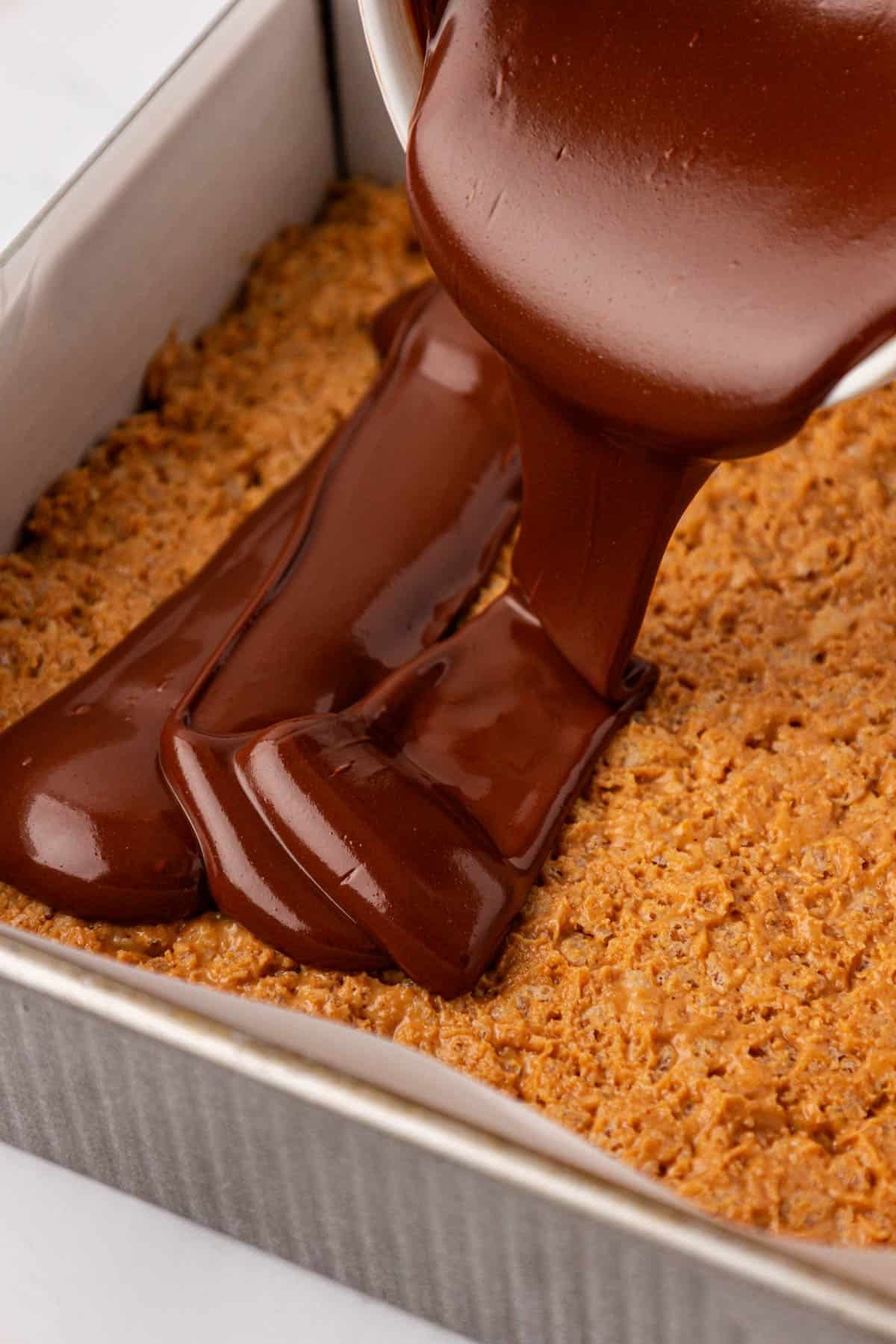 pouring the melted chocolate over the rice krispie bars